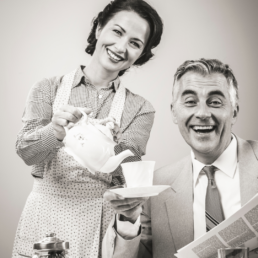 Black and white image of a 1950s woman pouring a cup of tea for her husband