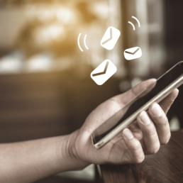 A hand holding a mobile phone reading emails